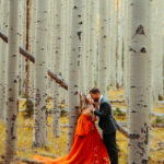 Engaged couple leaning against white aspen tree with yellow leaves in Flagstaff, Arizona.