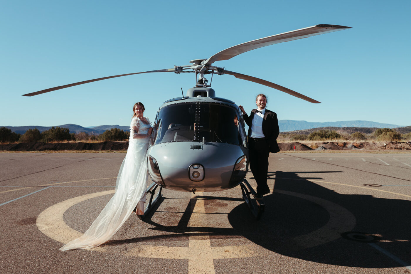 A bride and groom standing on a helicopter on their adventure elopement in Sedona, Arizona.