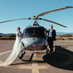 A bride and groom standing on a helicopter on their adventure elopement in Sedona, Arizona.