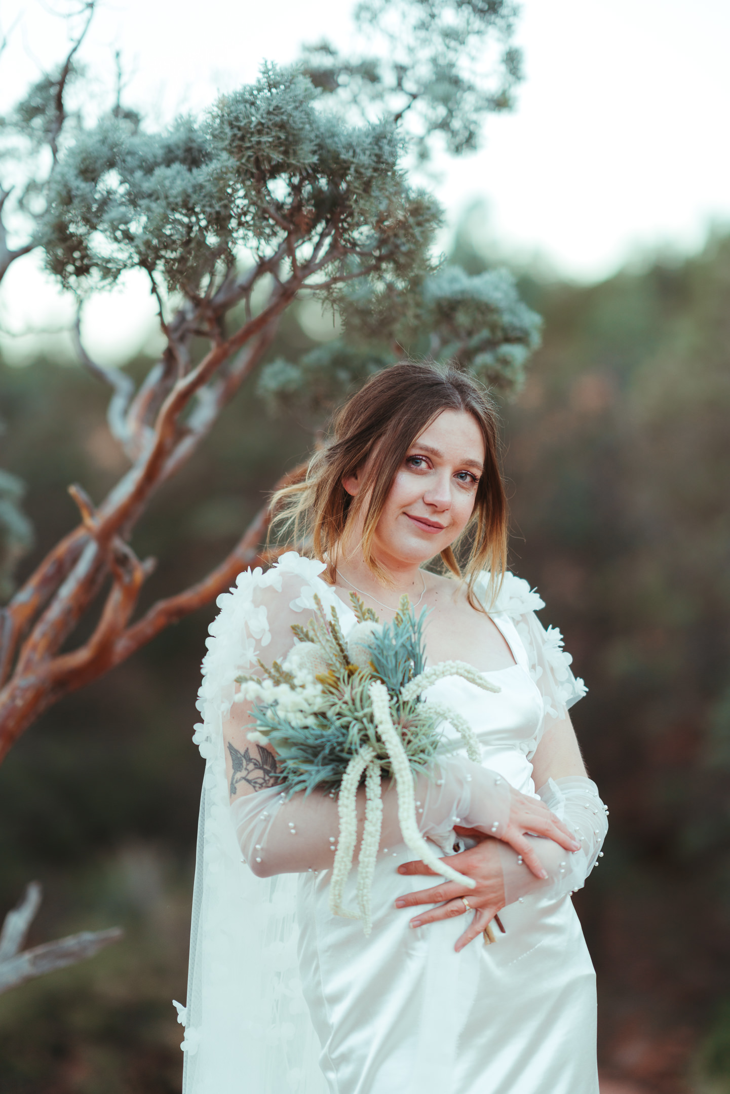 Bride holding juniper bouquet before elopement ceremony.