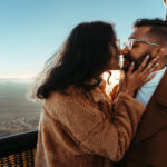 A newly engaged couple about to kiss after a hot air balloon proposal at sunrise over Phoenix, Arizona.